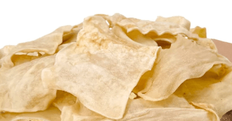 Pile of thin, tan, rectangular Beef Collagen Chips dog chews with wavy edges.