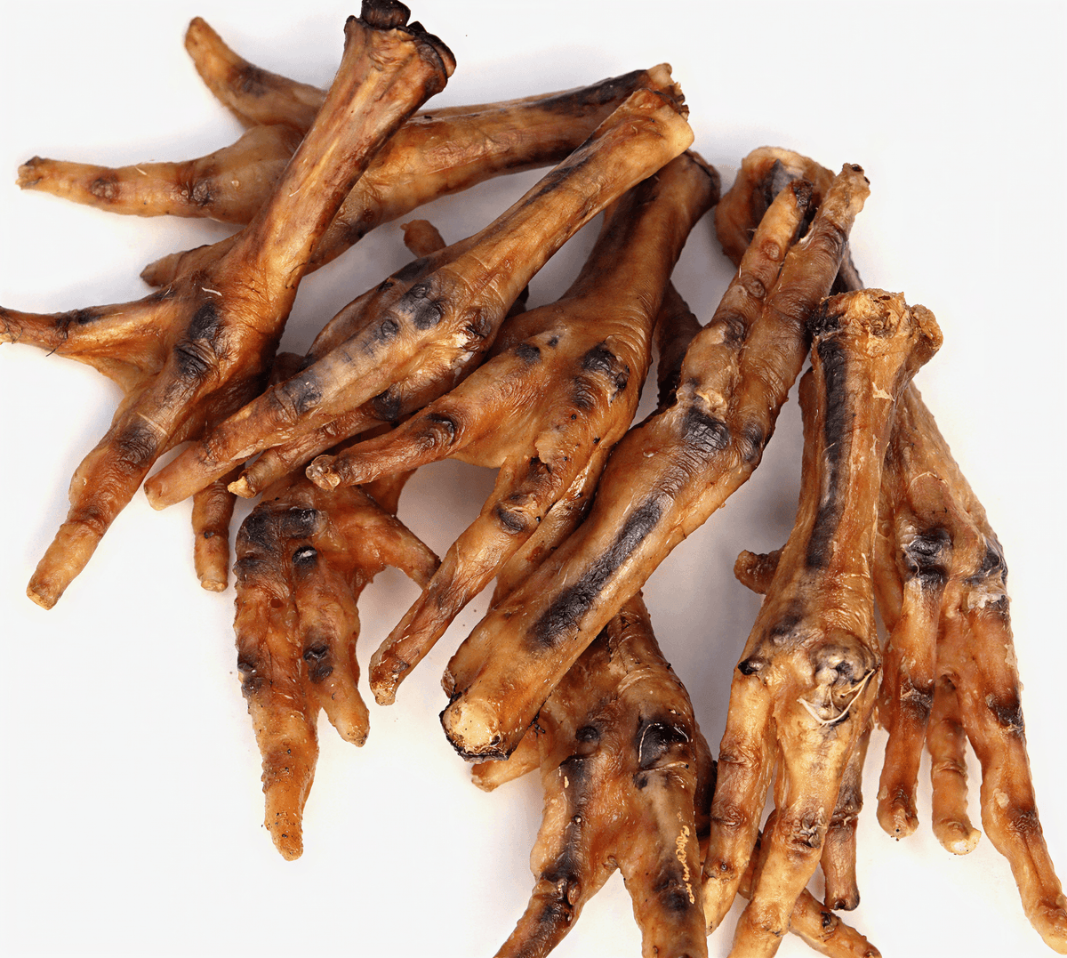 A pile of ten dried, golden-brown chicken feet dog chews scattered on a white background.